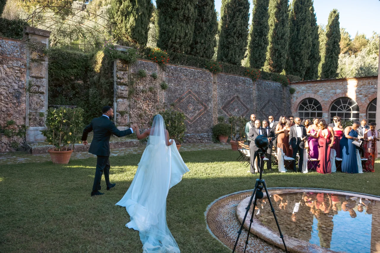 Pareja entrando en la celebración, con una cámara sobre trípode en primer plano